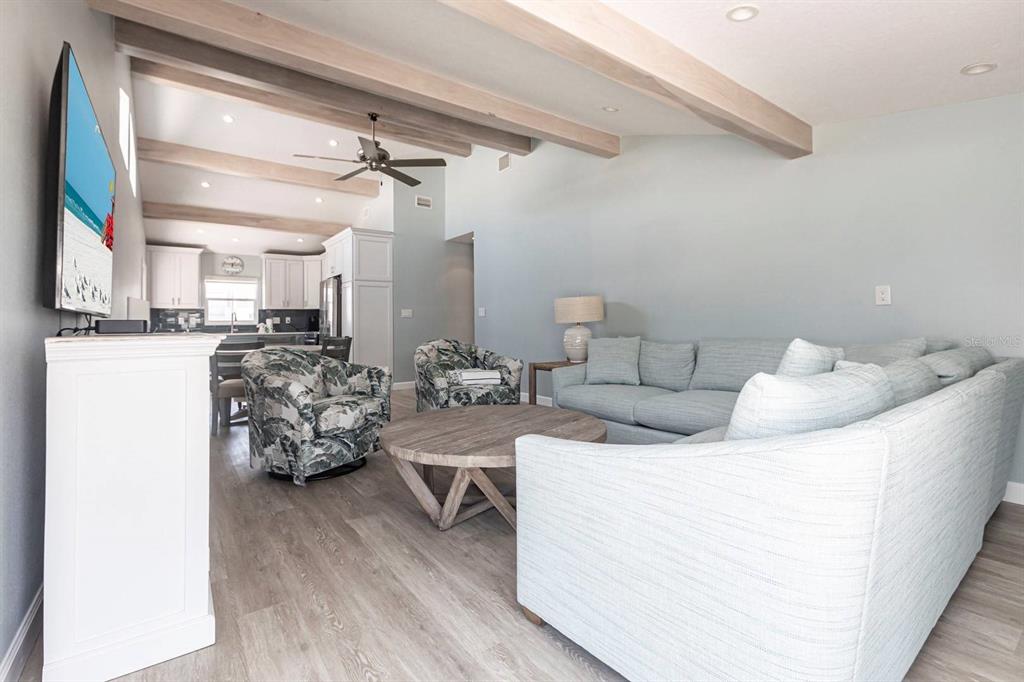 A living room features light wood-look flooring, vaulted ceilings with exposed beams, and a sectional sofa — 6020 MIDNIGHT PASS ROAD UNIT 64, SARASOTA, FL