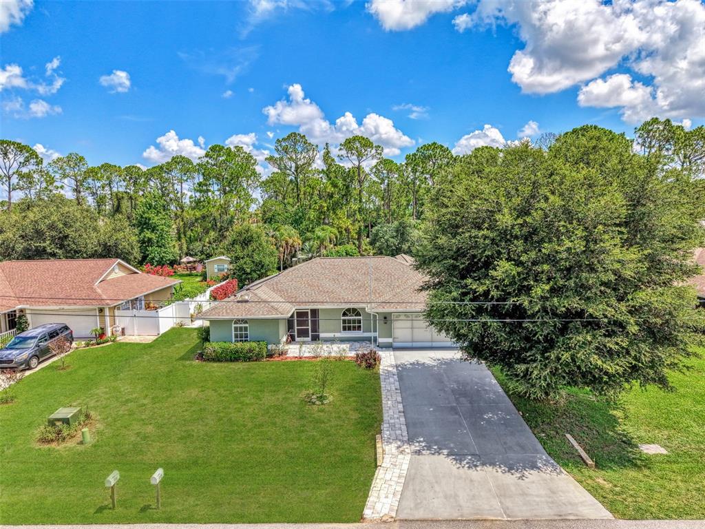 An aerial view of a single-story house with a green exterior, driveway, and large tree — 3706 SLAYTON AVENUE, NORTH PORT, FL
