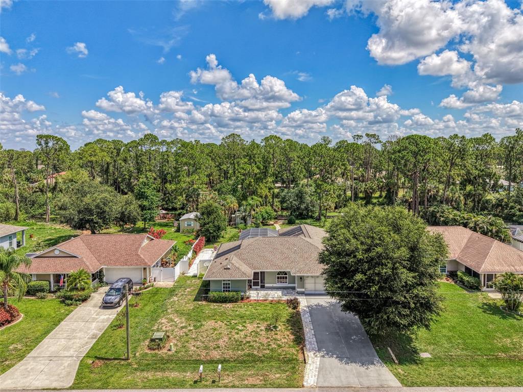 An aerial view shows three suburban houses with driveways and lawns against a wooded background — 3706 SLAYTON AVENUE, NORTH PORT, FL
