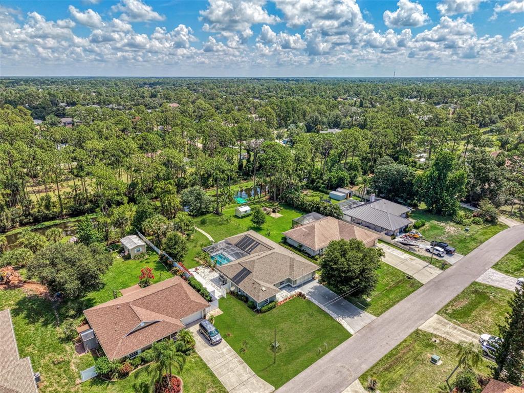An aerial view shows suburban houses with swimming pools and driveways surrounded by dense trees — 3706 SLAYTON AVENUE, NORTH PORT, FL
