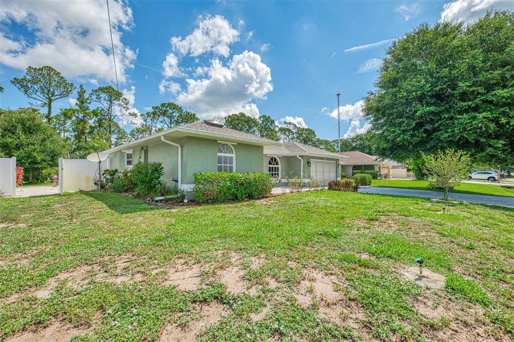 A single-story green house with a garage and a large front lawn under a blue sky — 3706 SLAYTON AVENUE, NORTH PORT, FL
