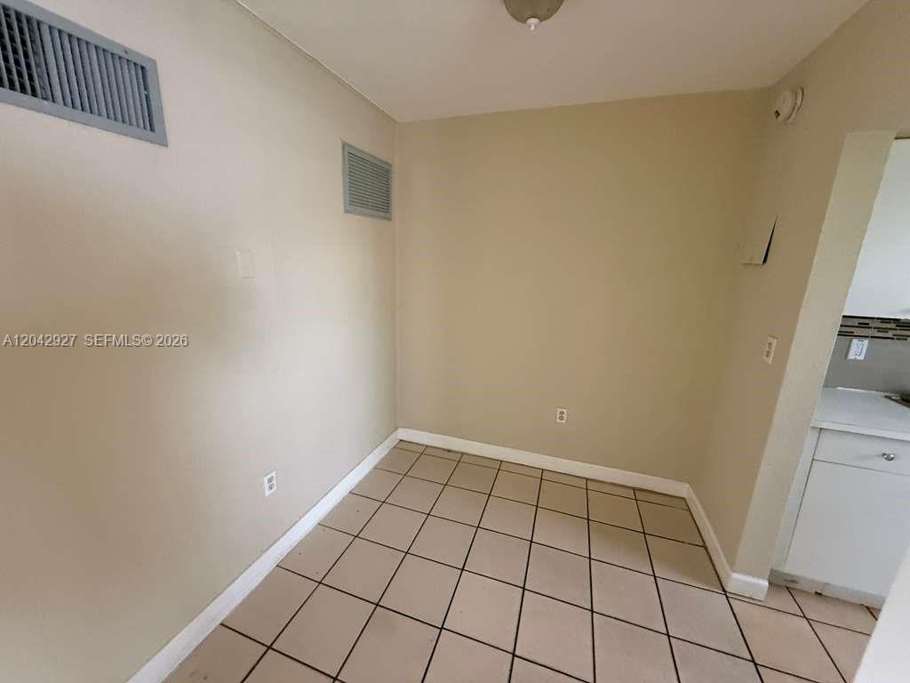 An empty room features beige walls, a tiled floor, and two wall-mounted air vents — 1255 W 49th Pl # H202, Hialeah FL 33012, HIALEAH, FL