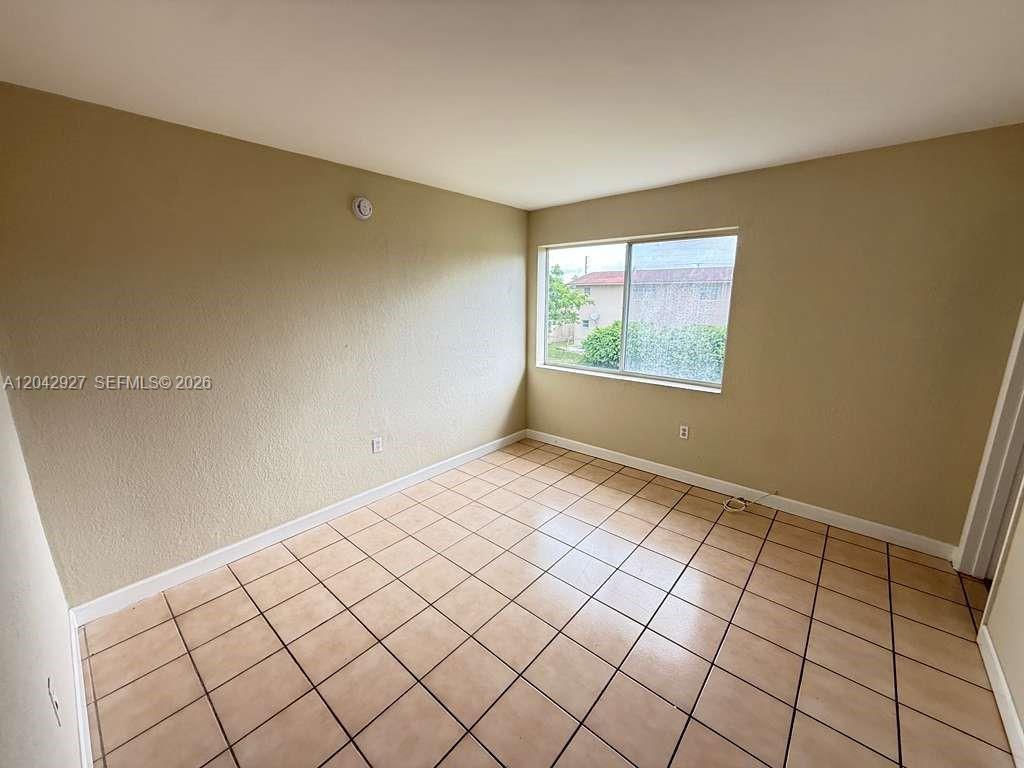An empty room features beige walls, a single window, and light-colored square floor tiles — 1255 W 49th Pl # H202, Hialeah FL 33012, HIALEAH, FL