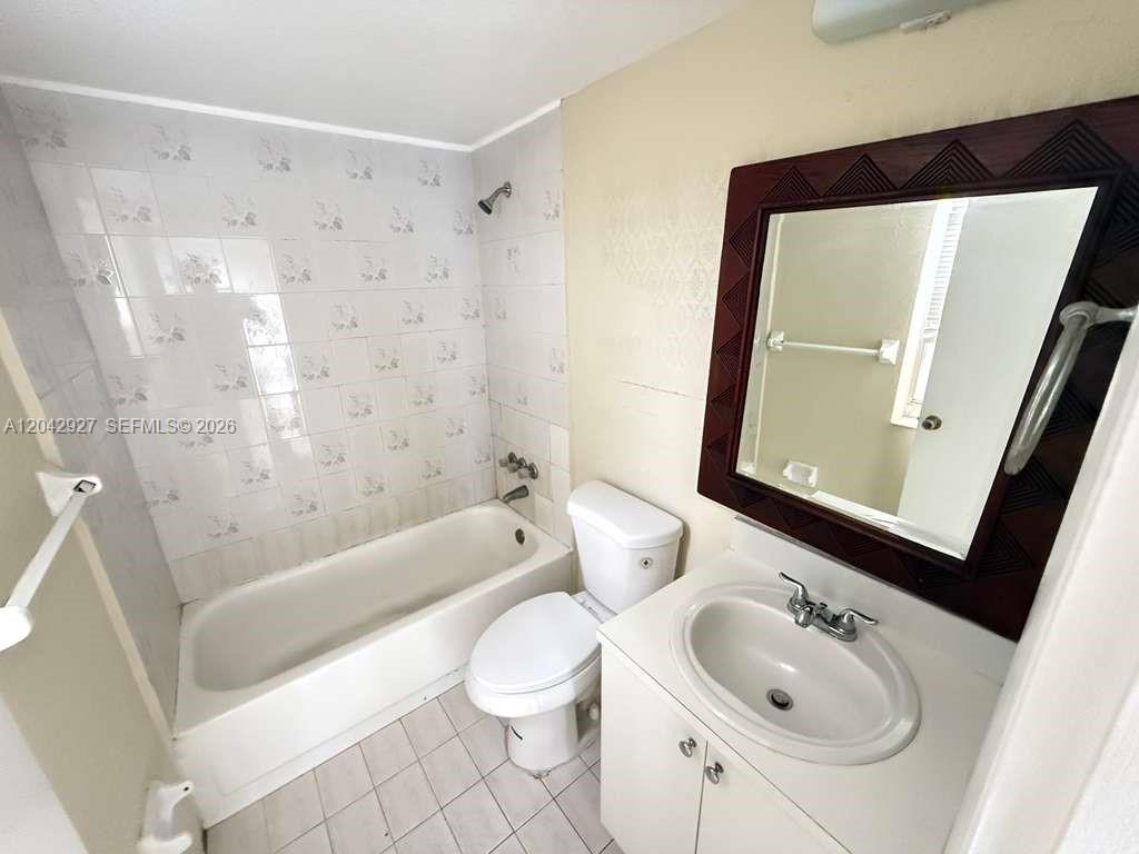 A bathroom features a white bathtub, a toilet, and a vanity with a mirror — 1255 W 49th Pl # H202, Hialeah FL 33012, HIALEAH, FL