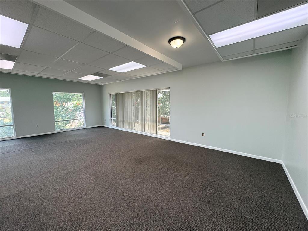 An empty office space features gray carpet, a drop ceiling with recessed lights, and large windows — 2110 DREW STREET (2nd floor), CLEARWATER, FL