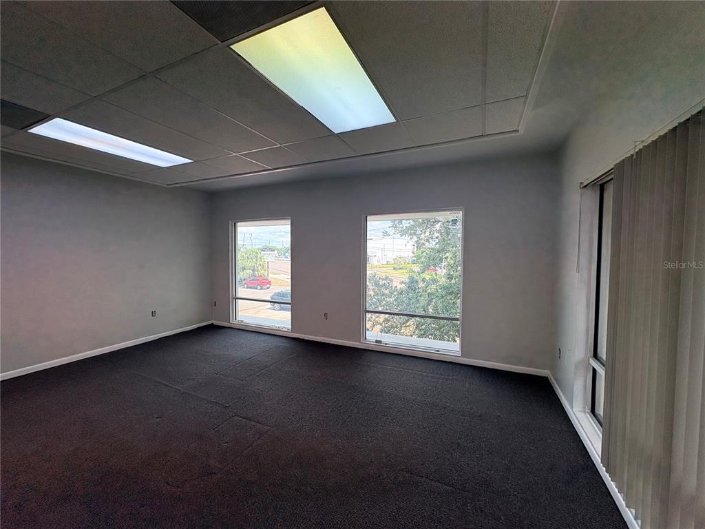 An empty office space features gray walls, dark carpeting, drop ceiling lights, and three windows — 2110 DREW STREET (2nd floor), CLEARWATER, FL