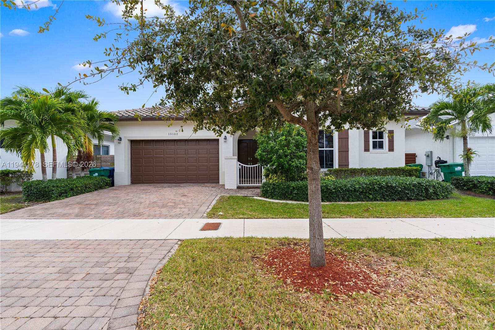 A single-story house features a brown garage door, a paved driveway, and a front tree — 15102 SW 177th Ter, Miami FL 33187, MIAMI, FL