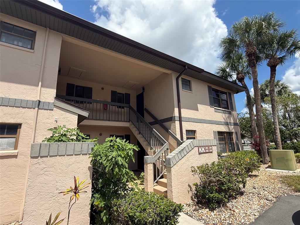 A two-story apartment building exterior features a staircase leading to an upper-level walkway — 19505 QUESADA AVENUE UNIT KK204, PORT CHARLOTTE, FL