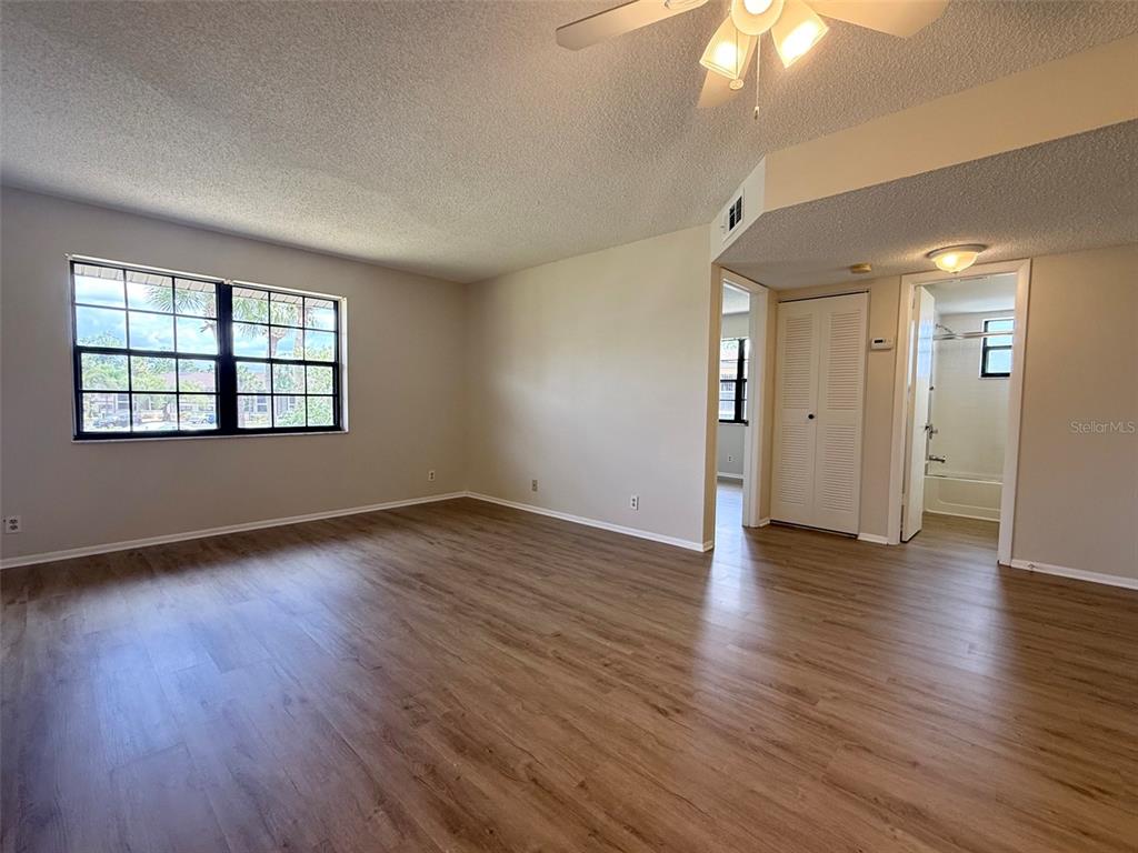 An empty room with wood-look flooring, a ceiling fan, and a window — 19505 QUESADA AVENUE UNIT KK204, PORT CHARLOTTE, FL