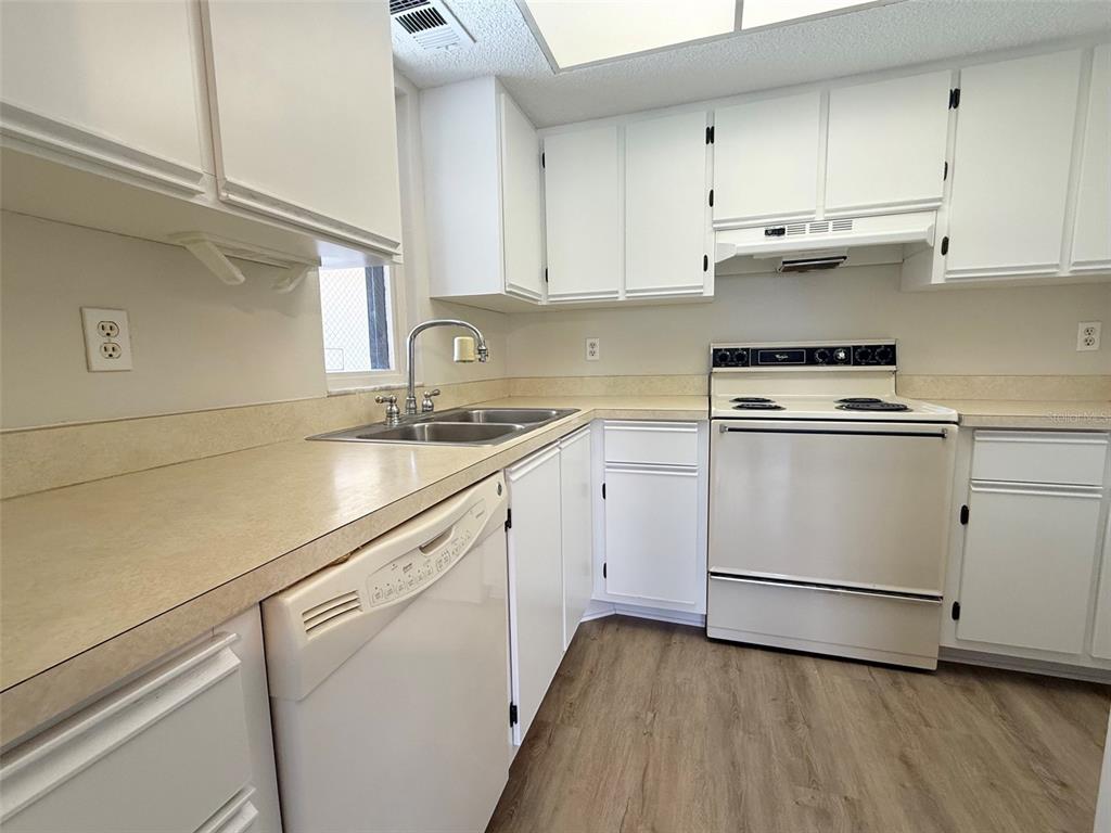 A kitchen features white cabinets, laminate countertops, a dishwasher, and a white electric range — 19505 QUESADA AVENUE UNIT KK204, PORT CHARLOTTE, FL