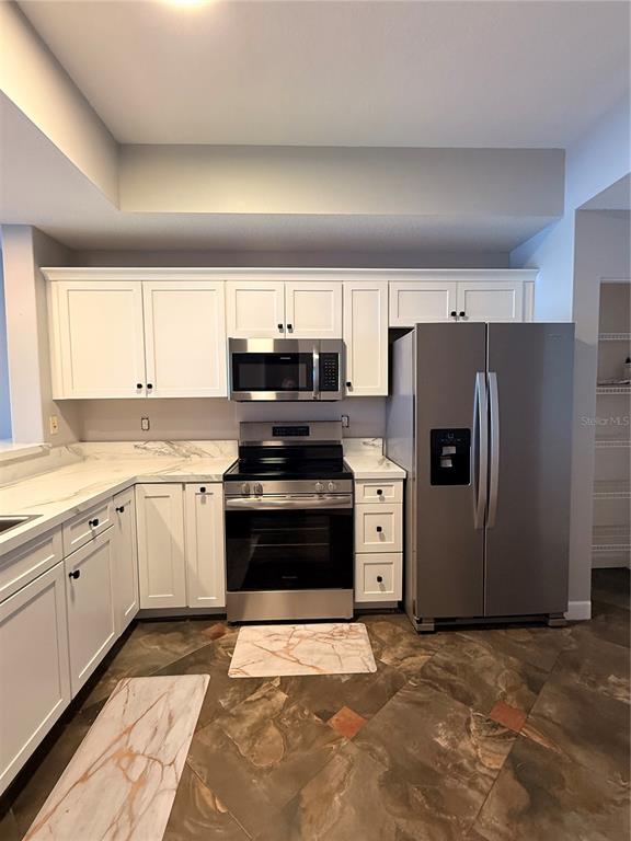 A white door is centered on a covered balcony with beige walls and brown flooring — 6312 BUFORD STREET UNIT 704, ORLANDO, FL