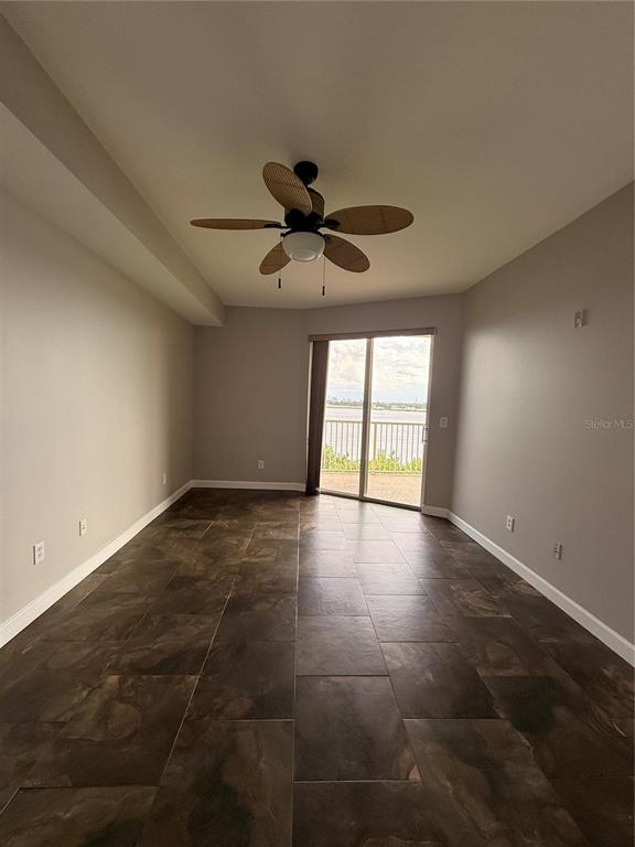 A kitchen with white cabinets and marble-look countertops overlooks an open living area with tile — 6312 BUFORD STREET UNIT 704, ORLANDO, FL