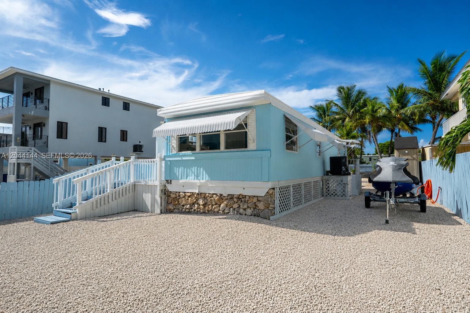 A light blue mobile home sits on a gravel lot with a white staircase — 768 Michael Dr, Key Largo FL 33037, KEY LARGO, FL