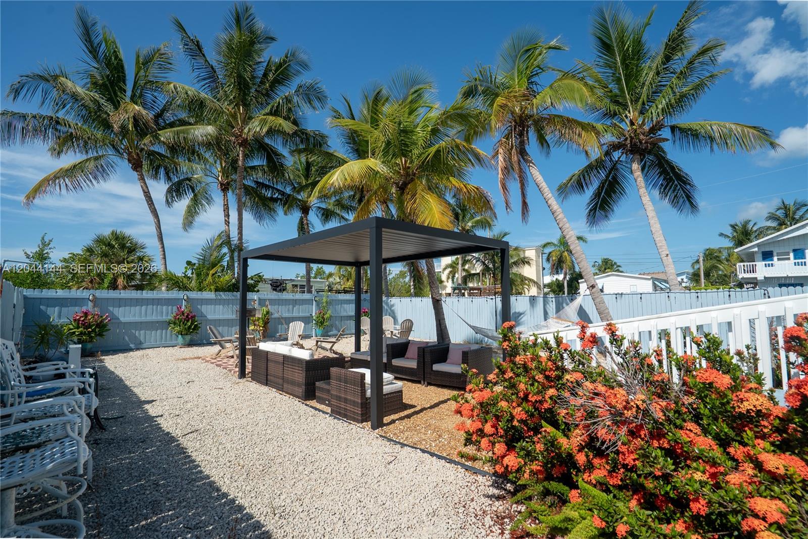 A backyard features a gravel patio, a modern pergola, patio furniture, and palm trees — 768 Michael Dr, Key Largo FL 33037, KEY LARGO, FL