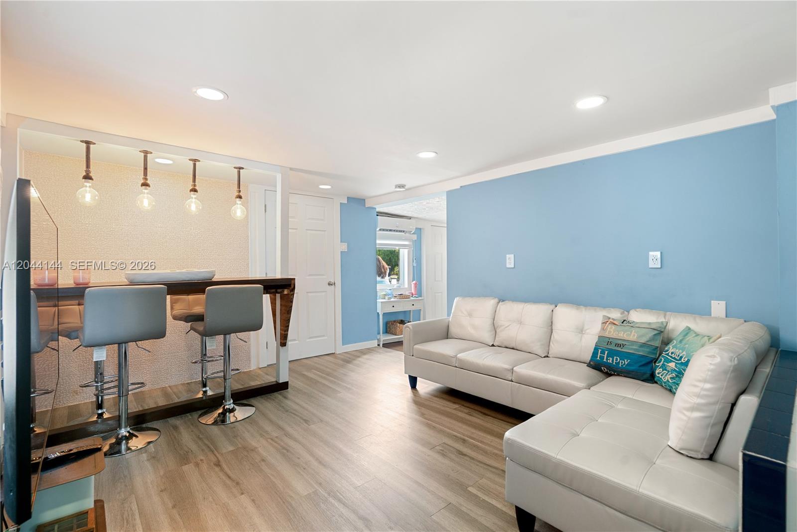 A living room features a bar area with stools, light wood flooring, and blue walls — 768 Michael Dr, Key Largo FL 33037, KEY LARGO, FL