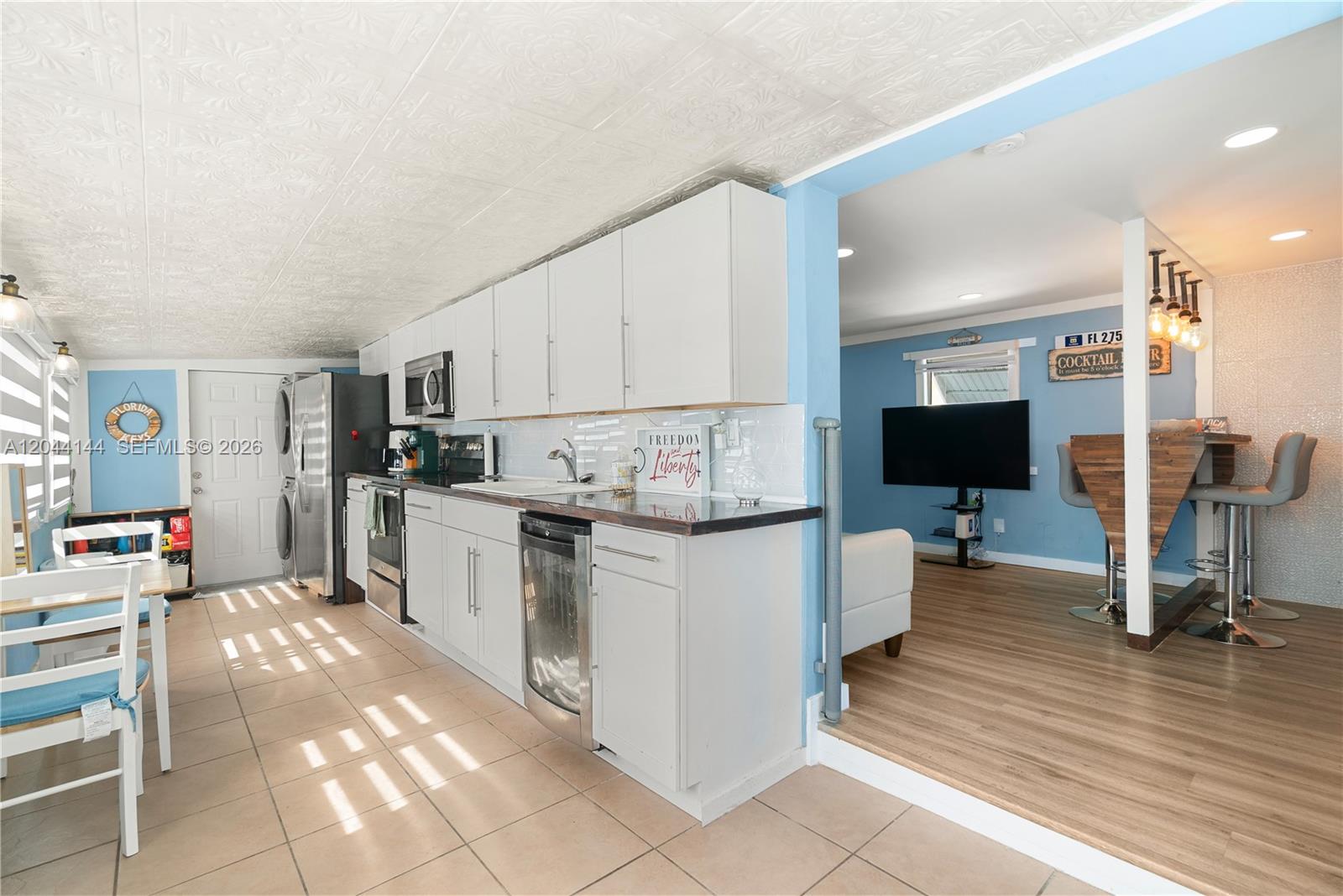 A kitchen with white cabinets and tile flooring transitions into a blue-walled living area — 768 Michael Dr, Key Largo FL 33037, KEY LARGO, FL
