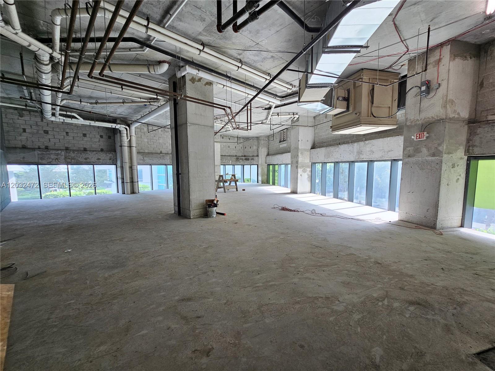 An unfinished commercial space features exposed concrete ceilings, industrial piping, and floor-to-ceiling windows — 501 NE 31st St # 1, Miami FL 33137, MIAMI, FL