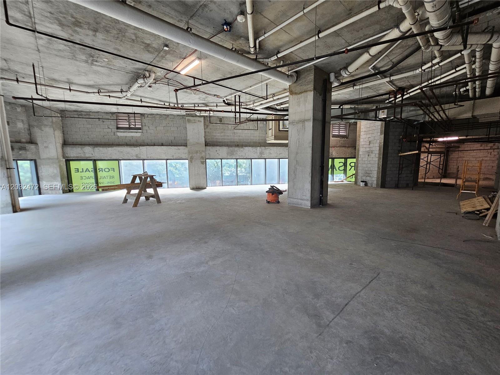 An unfinished commercial space features exposed concrete ceilings, utility pipes, and floor-to-ceiling windows — 501 NE 31st St # 1, Miami FL 33137, MIAMI, FL