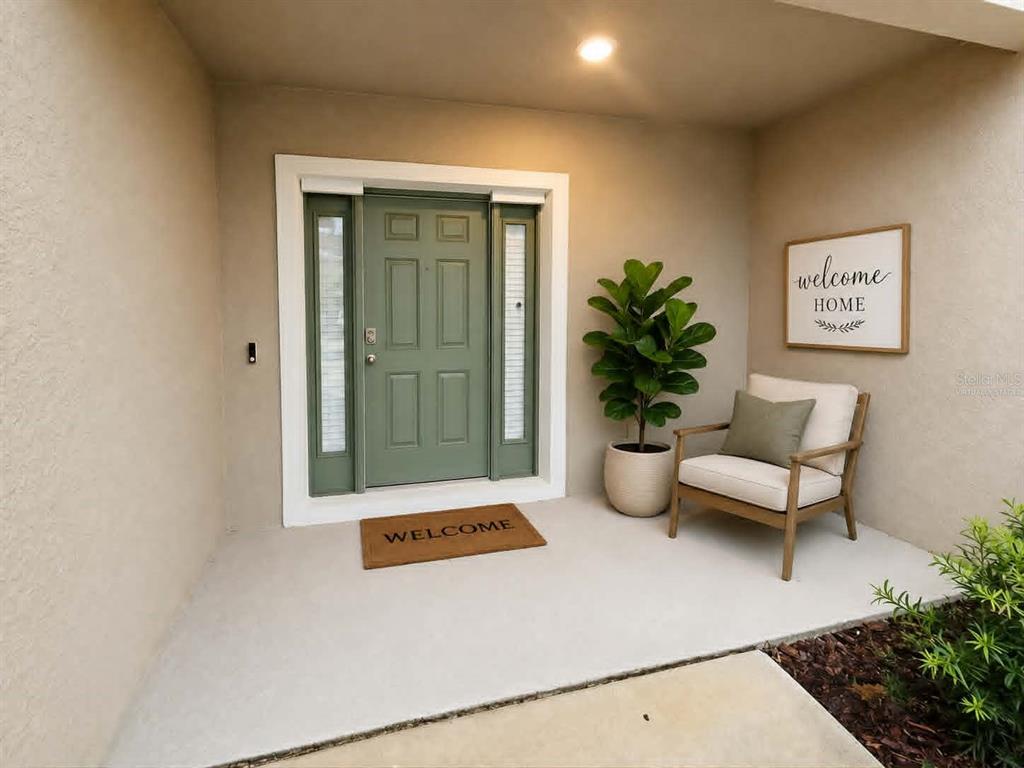 A front porch features a sage green door, a potted plant, and a wooden accent chair — 2732 SILVER CANOE DRIVE, EDGEWATER, FL