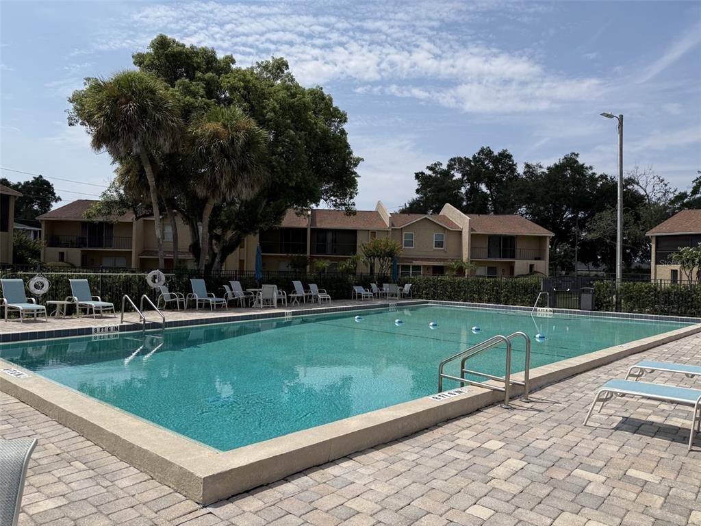 A rectangular swimming pool is surrounded by a paver deck and lounge chairs — 895 PARK LAKE CIRCLE UNIT 75, MAITLAND, FL