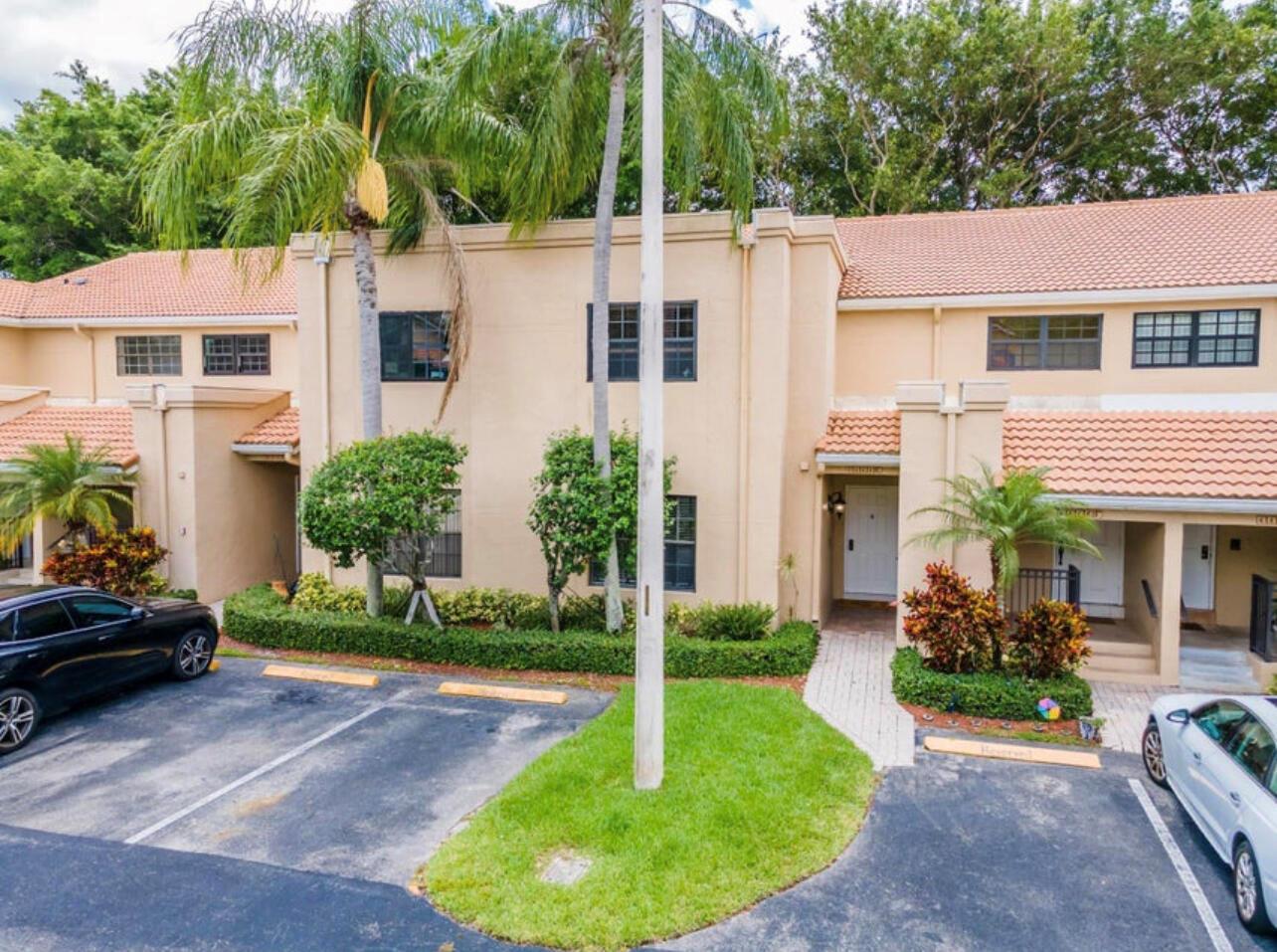 A two-story tan stucco townhouse with a tiled roof, palm trees, and a parking lot — 6666 Montego Bay Boulevard, Boca Raton FL 33433, BOCA RATON, FL