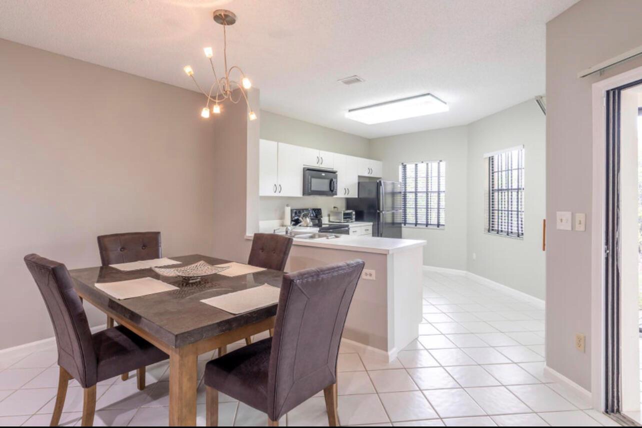 A dining area with a dark table and chairs sits adjacent to a white kitchen — 6666 Montego Bay Boulevard, Boca Raton FL 33433, BOCA RATON, FL