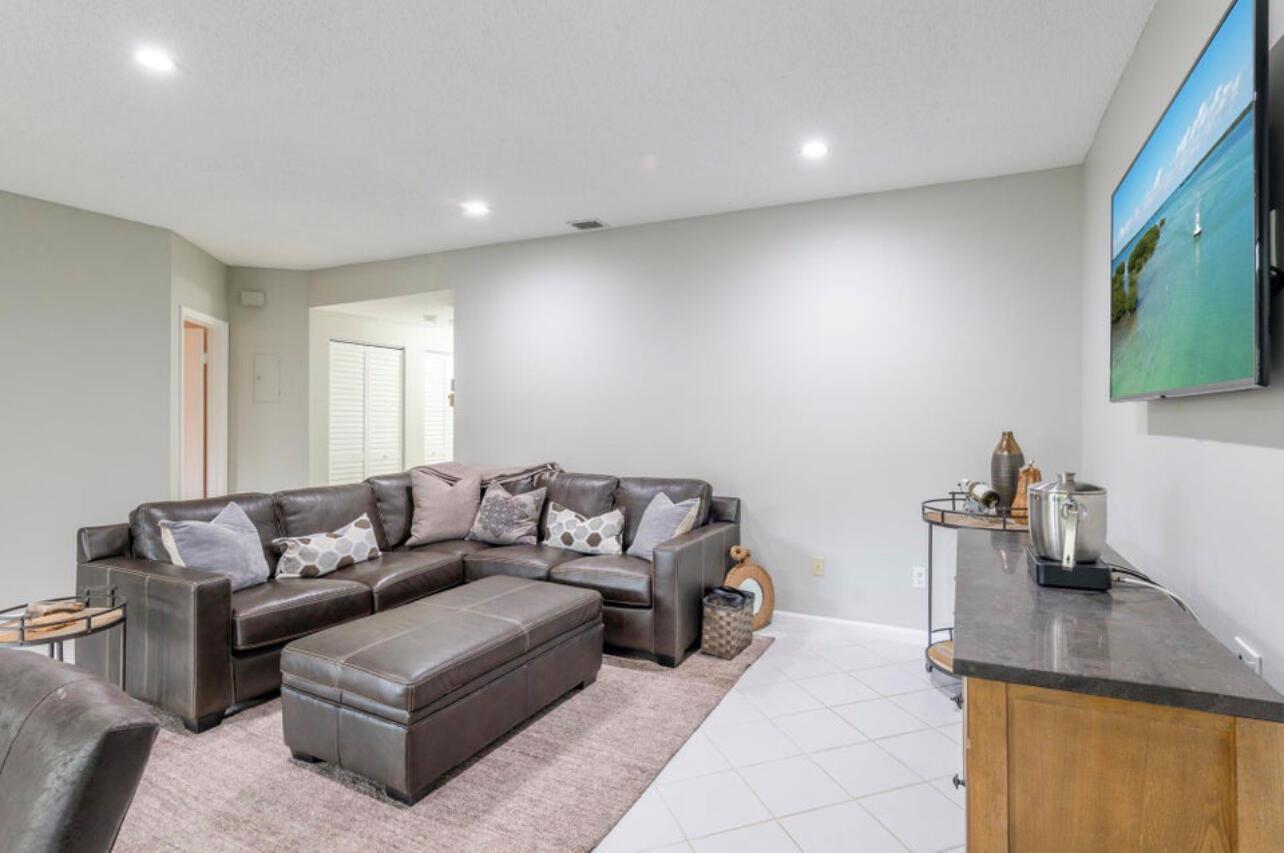 A living room features a dark leather sectional, a matching ottoman, and a wall-mounted television — 6666 Montego Bay Boulevard, Boca Raton FL 33433, BOCA RATON, FL