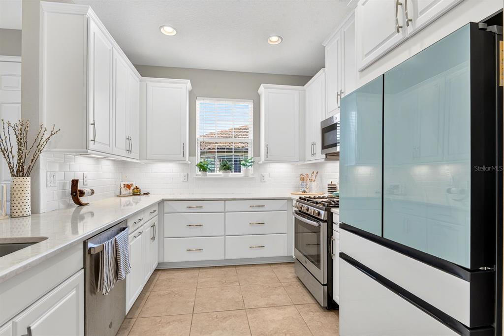 A kitchen with white cabinets, stainless steel appliances, a tile backsplash, and light-colored countertops — 5319 TALIAFERRO COURT, PALMETTO, FL