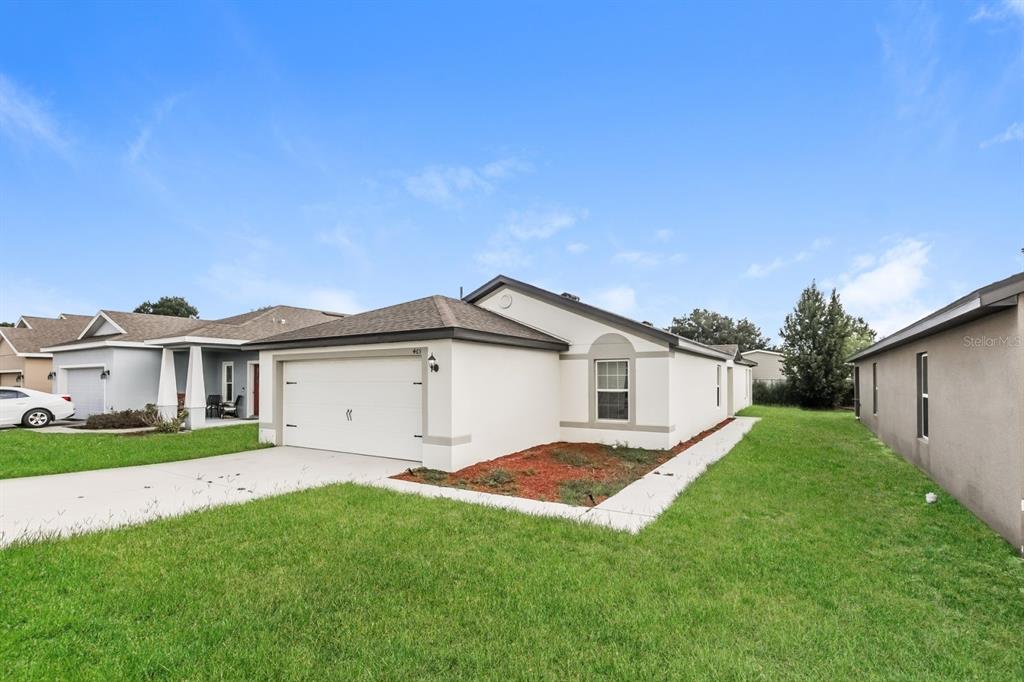 A single-story house with a white stucco exterior, a two-car garage, and a grassy yard — 465 KENSINGTON VIEW DRIVE, WINTER HAVEN, FL