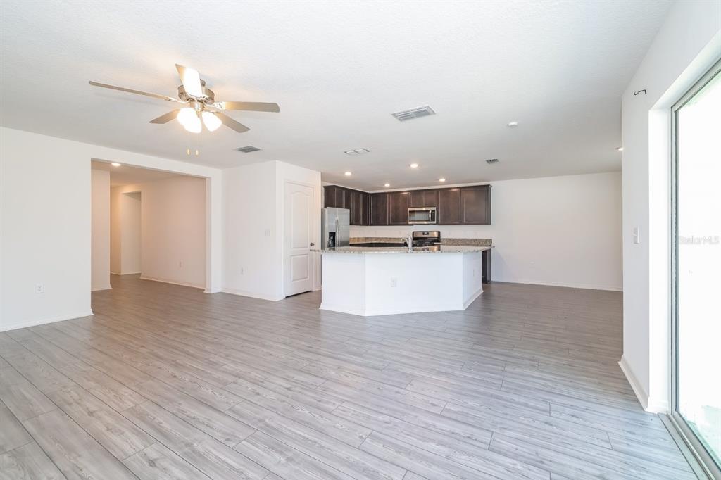 An open-concept kitchen with dark cabinets and a white island overlooks a spacious living area — 465 KENSINGTON VIEW DRIVE, WINTER HAVEN, FL
