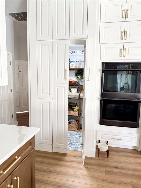 A kitchen features white cabinetry, a hidden pantry door, and a built-in double wall oven — 8027 BELSHIRE DRIVE, ORLANDO, FL
