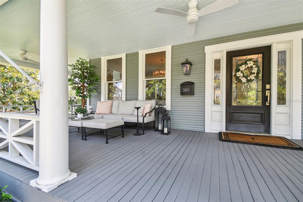 A covered front porch features gray decking, white columns, outdoor seating, and a dark front door — 1411 S ALBANY AVENUE, TAMPA, FL
