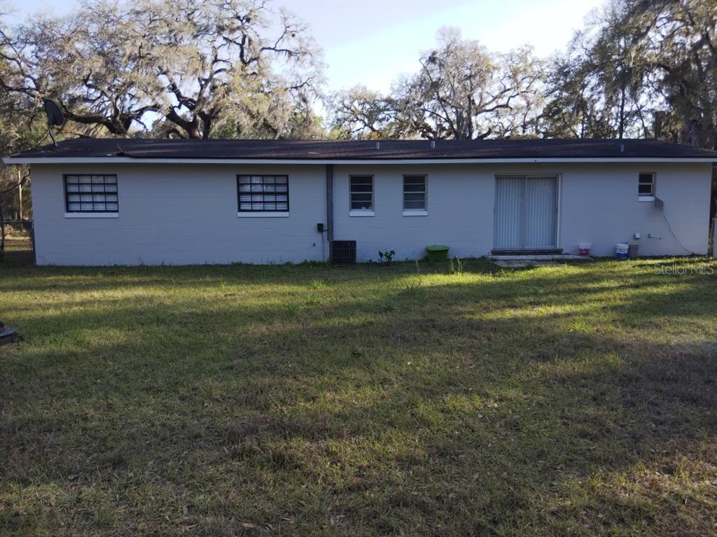 A view of the rear exterior of a single-story house with a grassy yard — 11031 NE 145TH STREET, FORT MC COY, FL