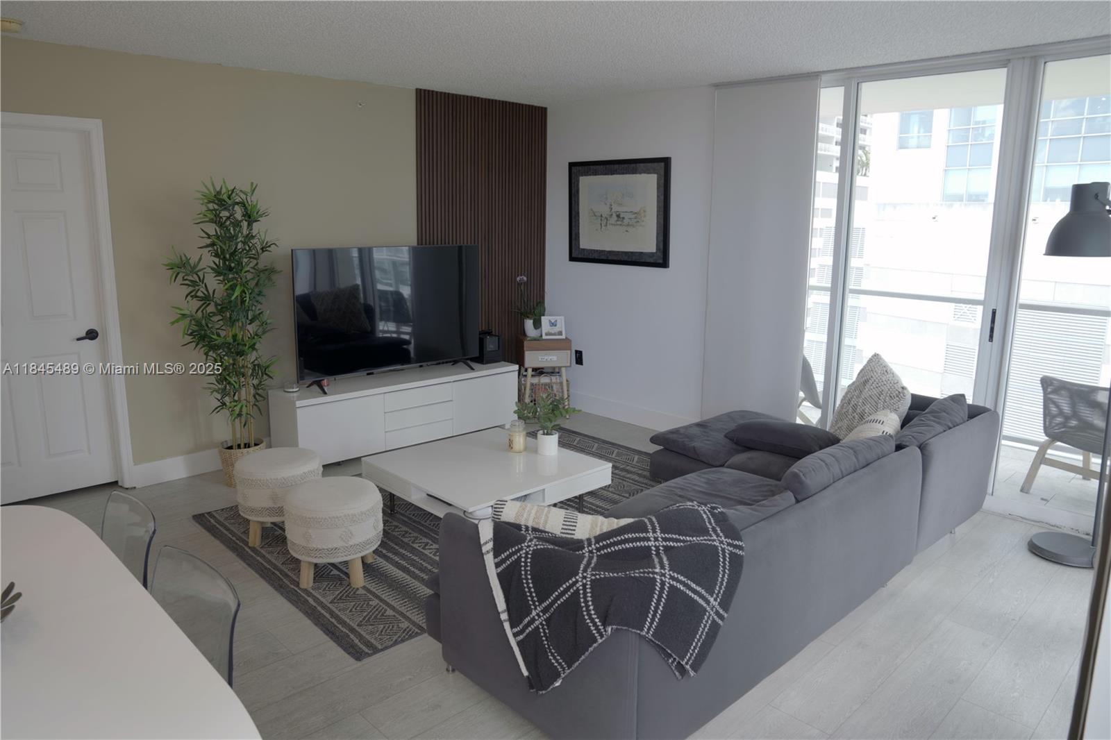 A living room features a gray sectional sofa, white coffee table, and a wood-slatted accent wall — 1155 Brickell Bay Dr # 902, Miami FL 33131, MIAMI, FL