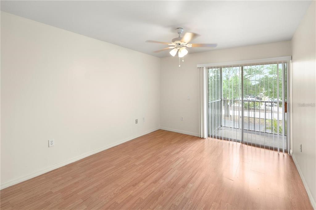 An empty room with light wood-look flooring, a ceiling fan, and a sliding glass door — 22278 VICK STREET UNIT A112, PUNTA GORDA, FL