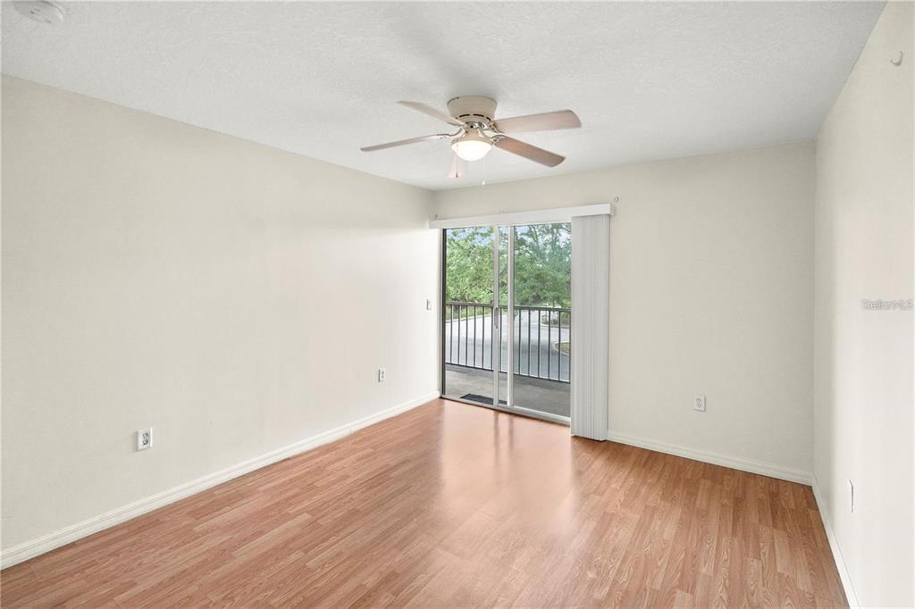 An empty bedroom features light-colored walls, wood-look flooring, a ceiling fan, and a sliding glass door — 22278 VICK STREET UNIT A112, PUNTA GORDA, FL