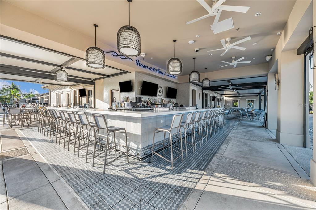 An outdoor bar area features a long counter with stools, pendant lighting, and ceiling fans — 204 RIVER ENCLAVE COURT, BRADENTON, FL