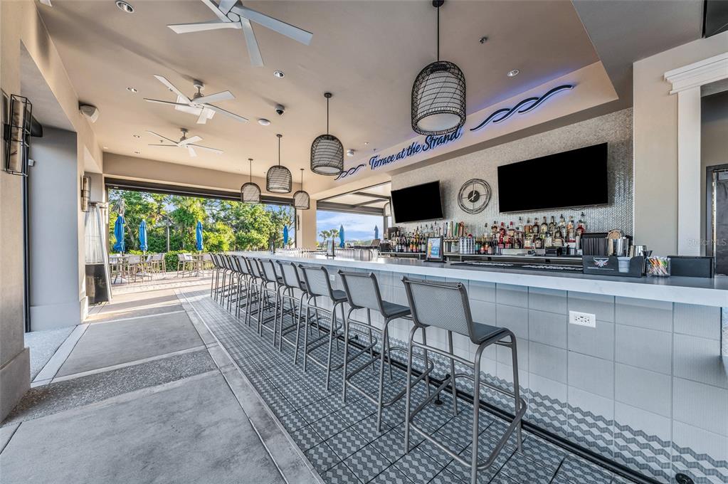An outdoor bar area features a long counter, bar stools, pendant lighting, and ceiling fans — 204 RIVER ENCLAVE COURT, BRADENTON, FL