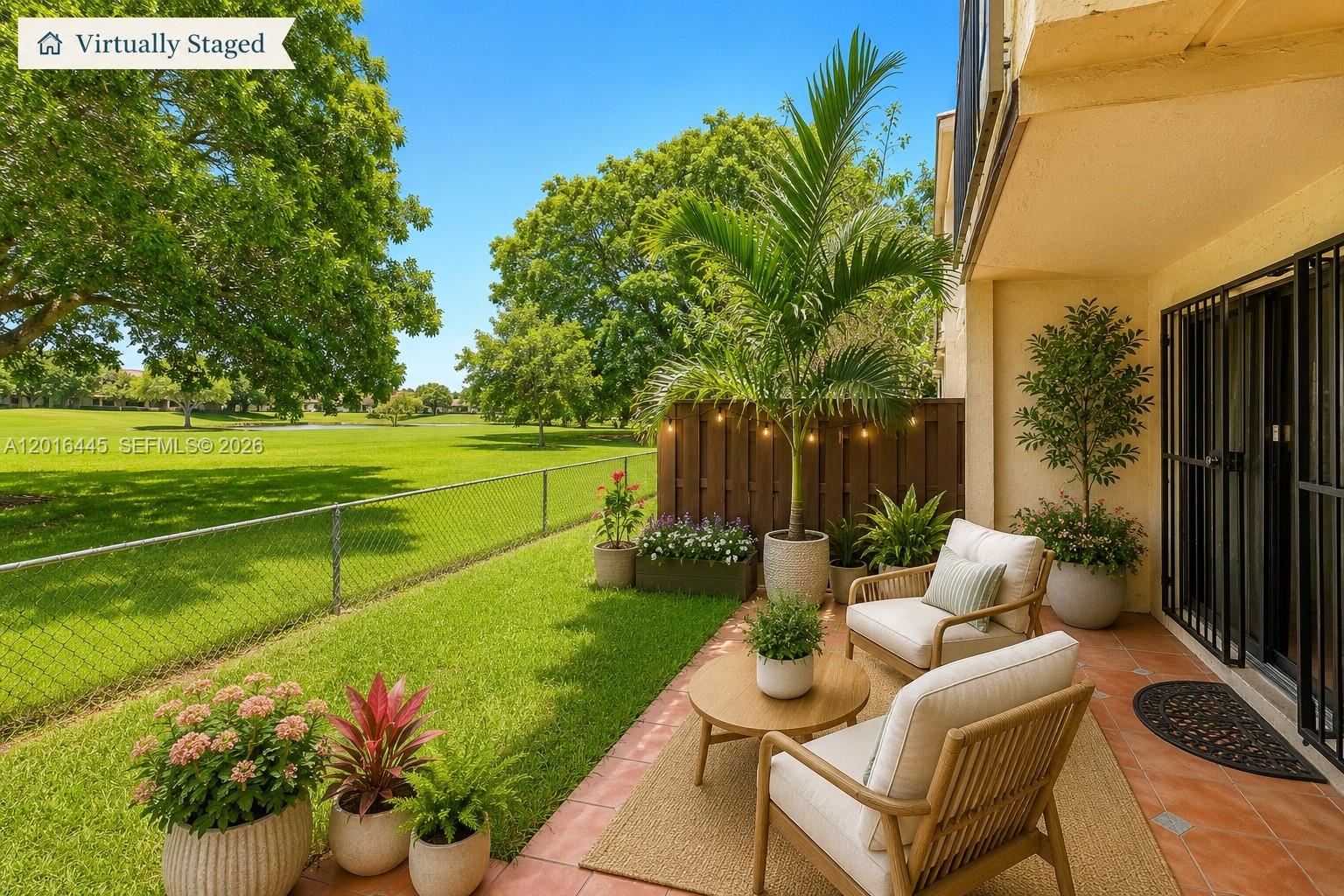A patio with two chairs, a small table, and potted plants overlooks a grassy field — 425 W Park Dr # 10, Miami FL 33172, MIAMI, FL