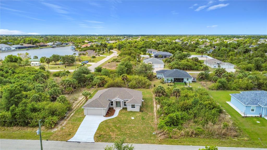 An aerial view shows a single-story house with a gray roof and driveway — 13503 AINSWORTH LANE, PORT CHARLOTTE, FL