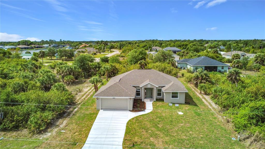 An aerial view shows a single-story house with a tan exterior, shingled roof, and driveway — 13503 AINSWORTH LANE, PORT CHARLOTTE, FL