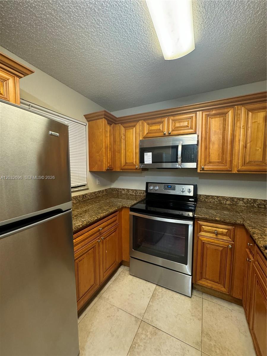 A kitchen features wood cabinets, granite countertops, and stainless steel appliances — 1640 Windorah Way # D, West Palm Beach FL 33411, WEST PALM BEACH, FL