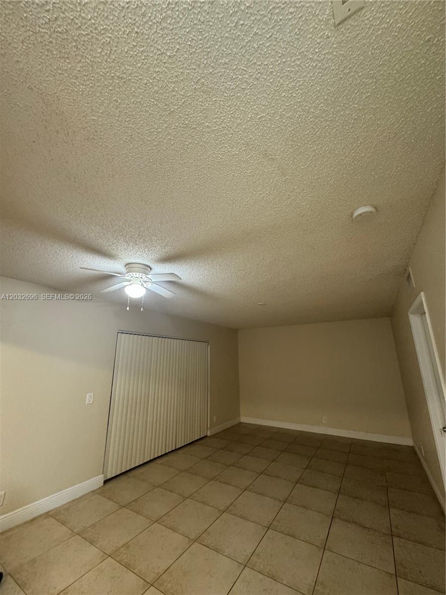 An empty room features beige walls, a tiled floor, and a ceiling fan — 1640 Windorah Way # D, West Palm Beach FL 33411, WEST PALM BEACH, FL