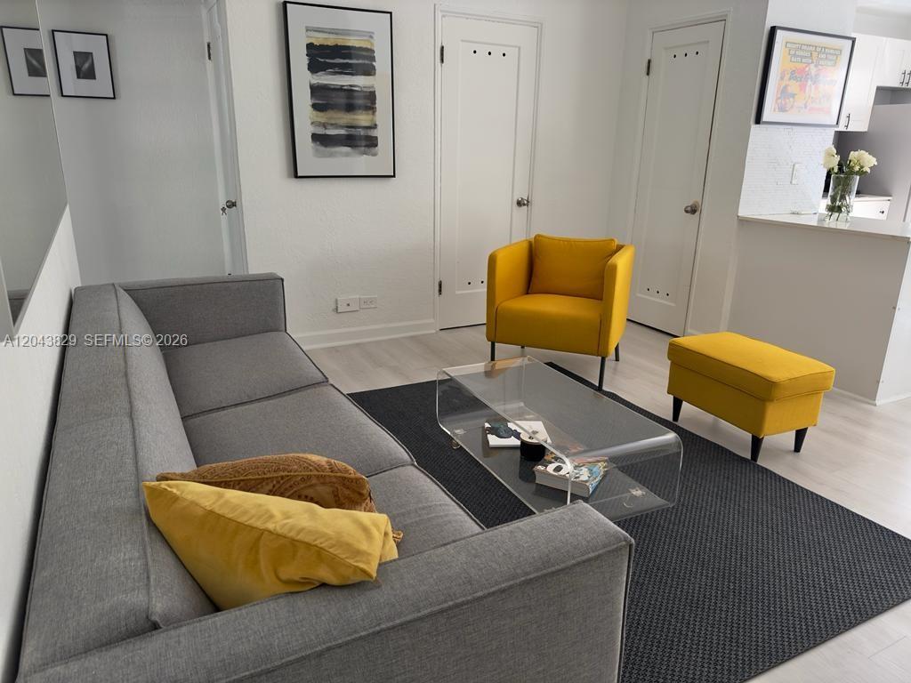 A living room features a grey sofa, a yellow armchair, a matching ottoman, and a glass table — 836 10th St # 5, Miami Beach FL 33139, MIAMI BEACH, FL