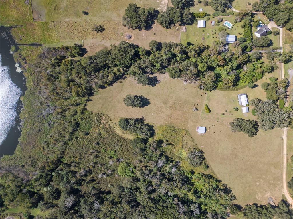 An aerial view shows a rural property with a house, outbuildings, pasture, and a lake — 32854 LISTER ROAD, DADE CITY, FL
