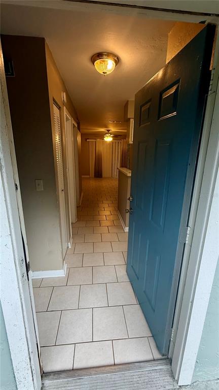 An open blue door reveals a tiled entryway leading into a hallway with two light fixtures — 4411 SW 34TH STREET UNIT 503, GAINESVILLE, FL
