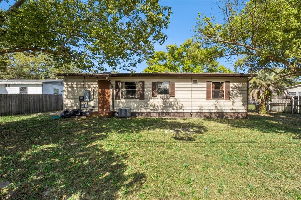 The exterior of a single-story house with tan siding, brown shutters, and a grassy yard — 217 COLONY DRIVE, CASSELBERRY, FL
