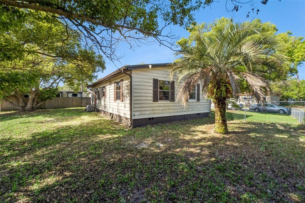 The exterior of a single-story house with light siding, dark shutters, and a palm tree — 217 COLONY DRIVE, CASSELBERRY, FL