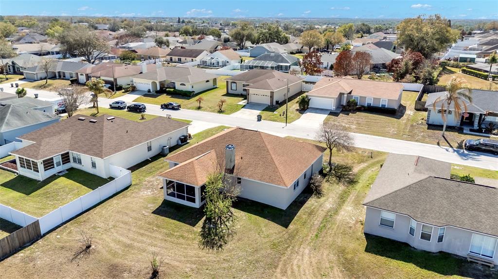 An aerial view shows several suburban houses with brown roofs and surrounding grassy yards — 7755 CANTERBURY CIRCLE, LAKELAND, FL