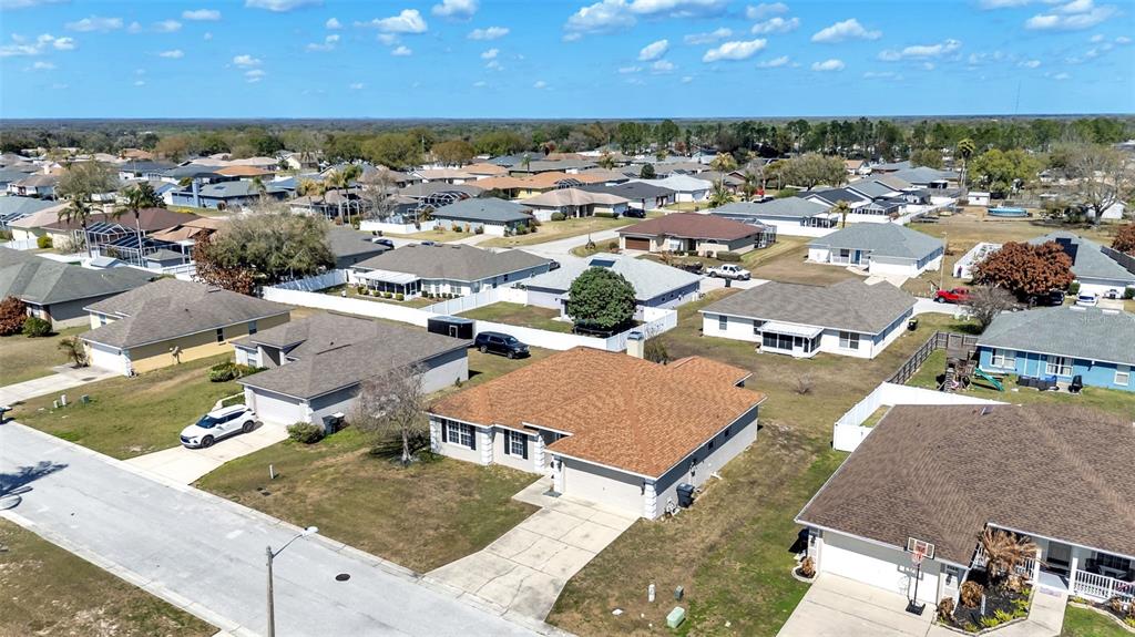 An aerial view shows a suburban neighborhood with single-family homes, driveways, and grassy yards — 7755 CANTERBURY CIRCLE, LAKELAND, FL